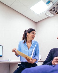 Patient and dentist smiling at each other in office