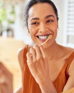 Woman smiling while brushing her teeth